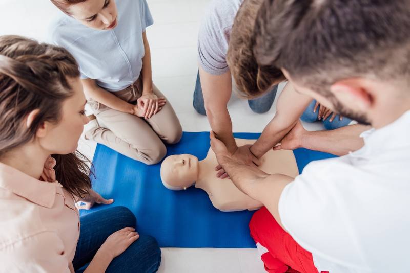 Students practicing chest compressions on a CPR training manikin