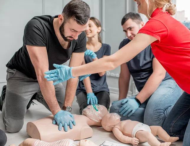 Instructor guiding students through adult and infant CPR practice